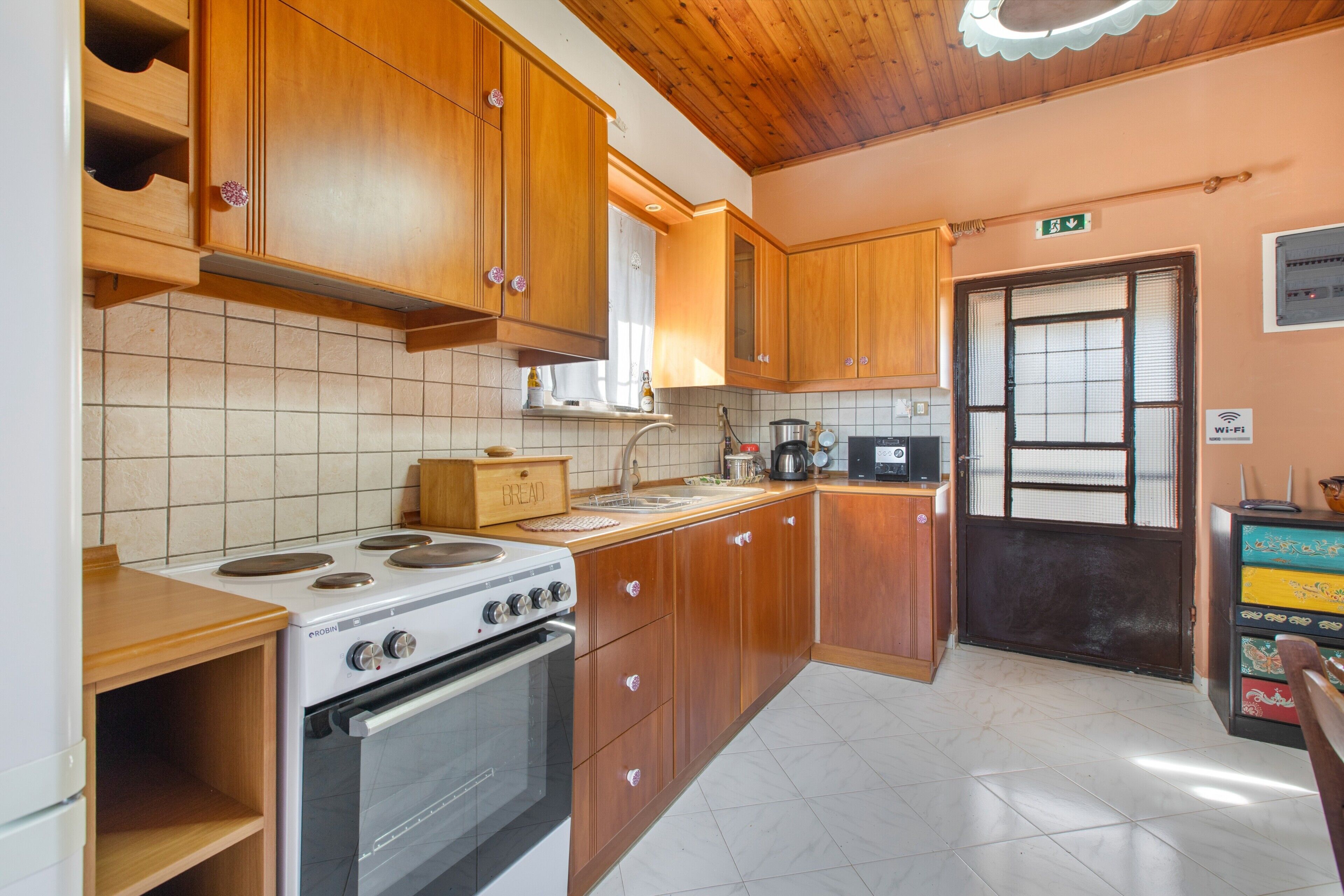 Una cucina con mobili in legno, un fornello, un forno, un microonde e uno schienale piastrellato.