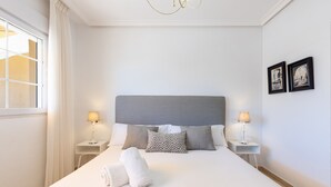 A neatly made bed with pillows, a bedside lamp, and a window with curtains. - Spectacular Penthouse Puerto Romano with Sea View, Shared Pool & Wi-Fi (Marbella)