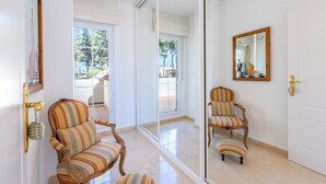 A room with two striped armchairs, a mirrored wall, and a sliding glass door leading to an outdoor area. - Spectacular Penthouse Puerto Romano with Sea View, Shared Pool & Wi-Fi (Marbella)