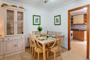Een eetruimte met een houten tafel, stoelen, een kast en lijstjes met foto's aan de muur.