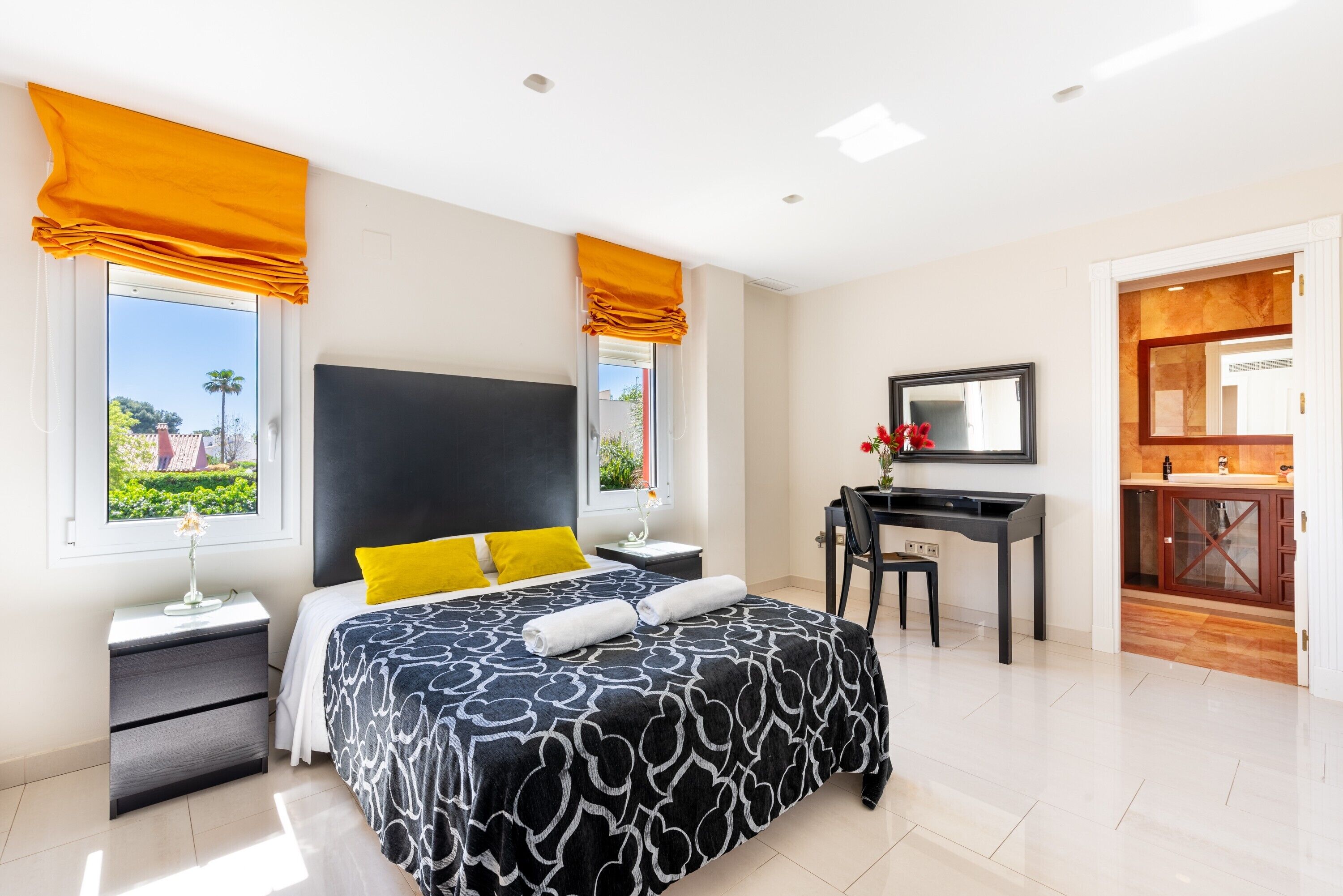 Une chambre d’hôtel moderne, dotée d’un grand lit, d’un bureau et d’une salle de bain visible à travers une porte ouverte.