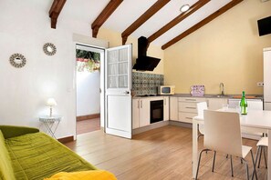 A compact living space with a kitchenette, a dining area, and a green sofa.