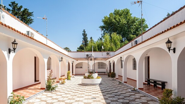 Un cortile con pavimento decorato, pareti bianche e archi.