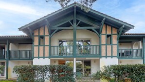 A two-story building with a balcony, a covered entrance, and a garden area. - Apartment "Bisbau" with Private Terrace, Private Garden & Shared Pools (Moliets-et-Maa)