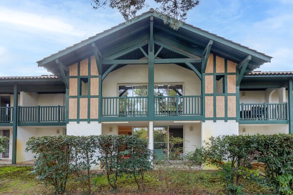 Un bâtiment à deux étages doté d’un balcon, d’une entrée couverte et d’un espace jardin.