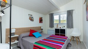 Ein Schlafzimmer mit Bett, Nachttisch und einem Vorhangfenster.