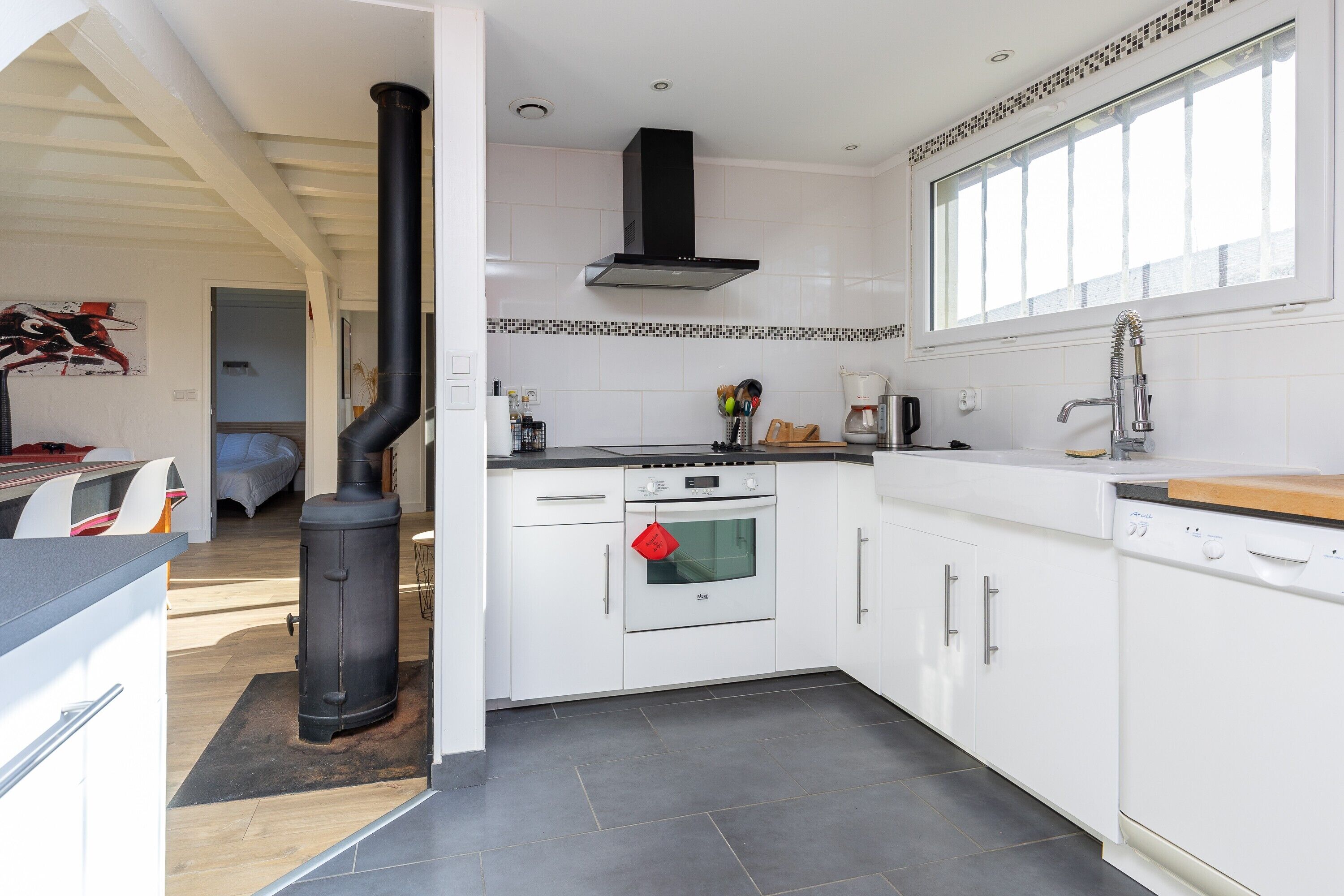 A modern kitchen with white cabinets, a black stove, an oven, and a dishwasher.