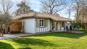 Ein Haus mit einem Ziegeldach, einer Veranda mit Stühlen und einem Rasen.
