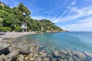 A coastal property with a stone building, clear waters, and lush greenery.