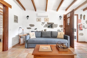 A cozy living room with a blue sofa, a wooden coffee table, and a stone wall.