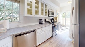 A modern kitchen with white cabinetry, a dishwasher, a coffee maker, and a refrigerator.