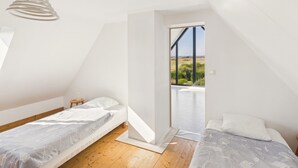 Camera da letto con due letti, pavimento in legno, lampadario e vista sull'esterno.