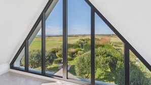 Una stanza con un'ampia finestra triangolare che si affaccia su un paesaggio verde.