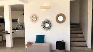 Una sala de estar moderna con un sofá, una mesa de centro y un espejo fijado a la pared.