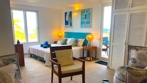 Habitación amplia con cama, una silla, una mesita y vistas al exterior.