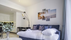 A modern hotel room with a large bed, a desk, and a dining area. - LUX - The Pad Executive Suite 4 (Dubai)