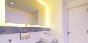 A modern bathroom with a white sink, a mirror with under-cabinet lighting, and a door to the right. - LUX - The Pad Executive Suite 4 (Dubai)