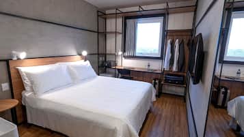 Habitación de hotel moderna con una cama grande, un escritorio, una silla, un televisor y un armario.