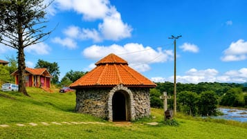 A stone building with a tiled roof, a stone archway entrance, and a grassy area with a path leading to it.