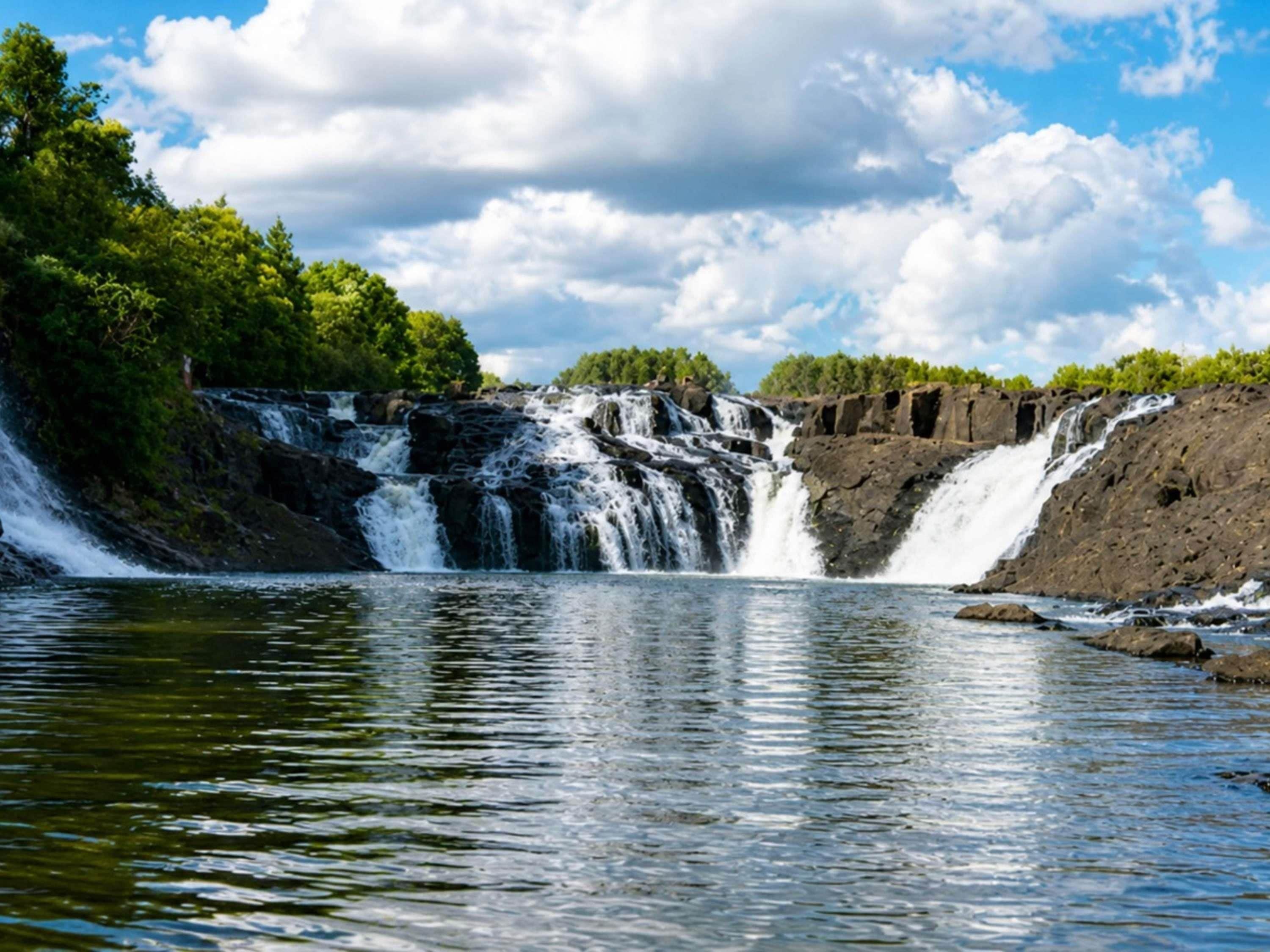 A waterfall with a rocky ledge and dense greenery.