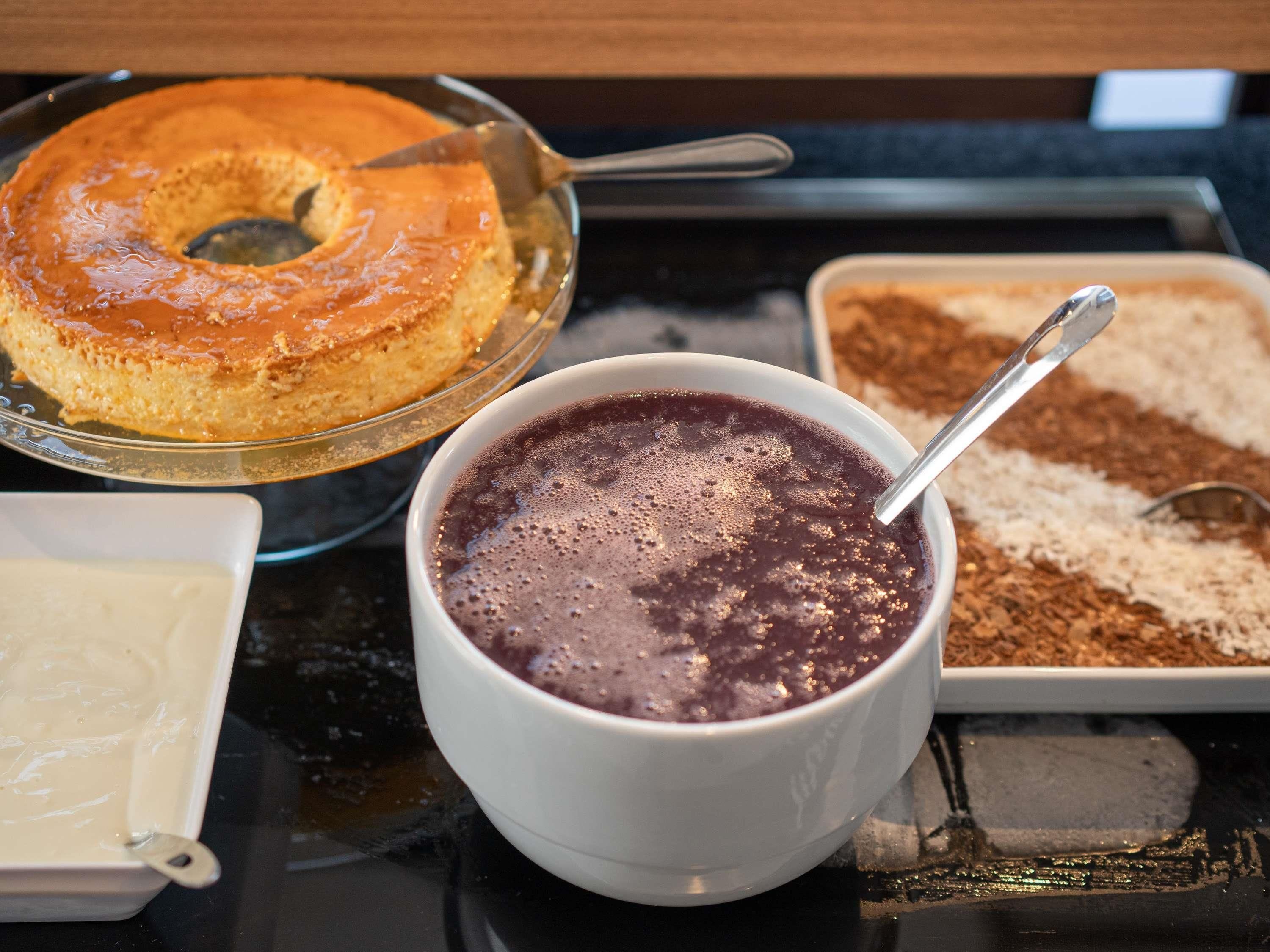 Ein Desserttisch mit Kuchen, einer Schüssel Schokoladenmousse und einer Schale Kakaopulver.