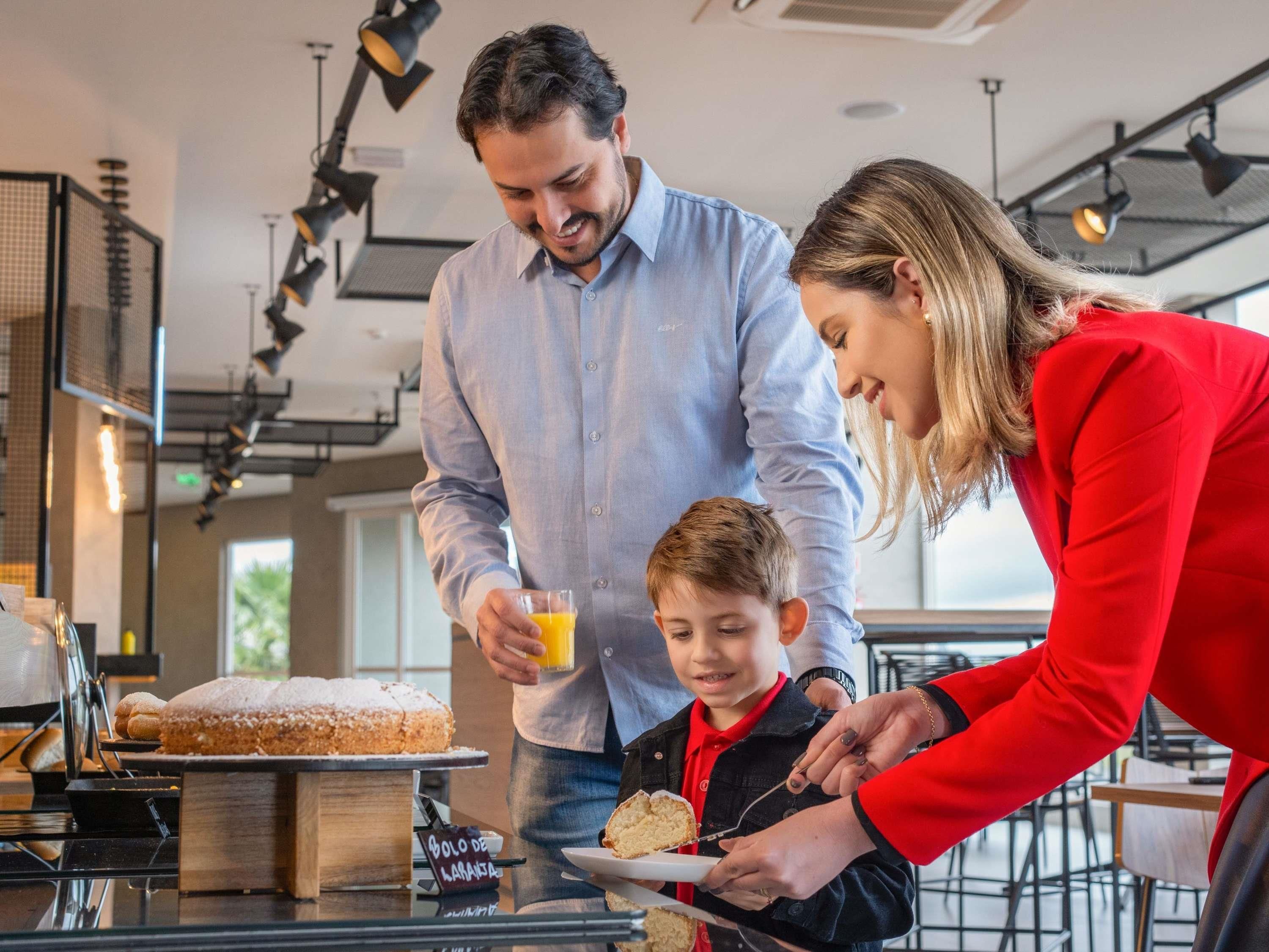 A family dining in a modern restaurant with a dessert display and a menu board visible.