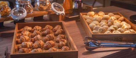 A buffet with various food items including croissants and bread rolls.