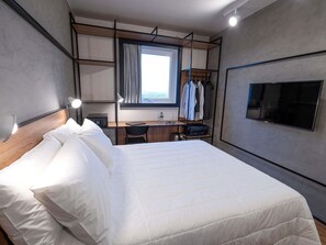 A hotel room with a bed, a desk with a chair, a TV, and a wardrobe. - Ibis Guarapuava (Guarapuava)