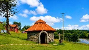 Un edificio de piedra con techo de tejas, un arco de piedra en la entrada y una zona verde con un sendero que lo lleva a él.