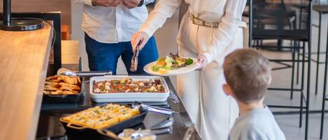 Una mesa de buffet con diversos platos y una persona sirviendo comida.