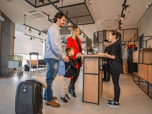 A modern interior with a reception desk, a child with a suitcase, and a woman in a red coat. - Ibis Guarapuava (Guarapuava)