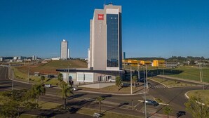 A modern hotel with a prominent 'ibis' logo, a parking lot, and a road intersection. - Ibis Guarapuava (Guarapuava)