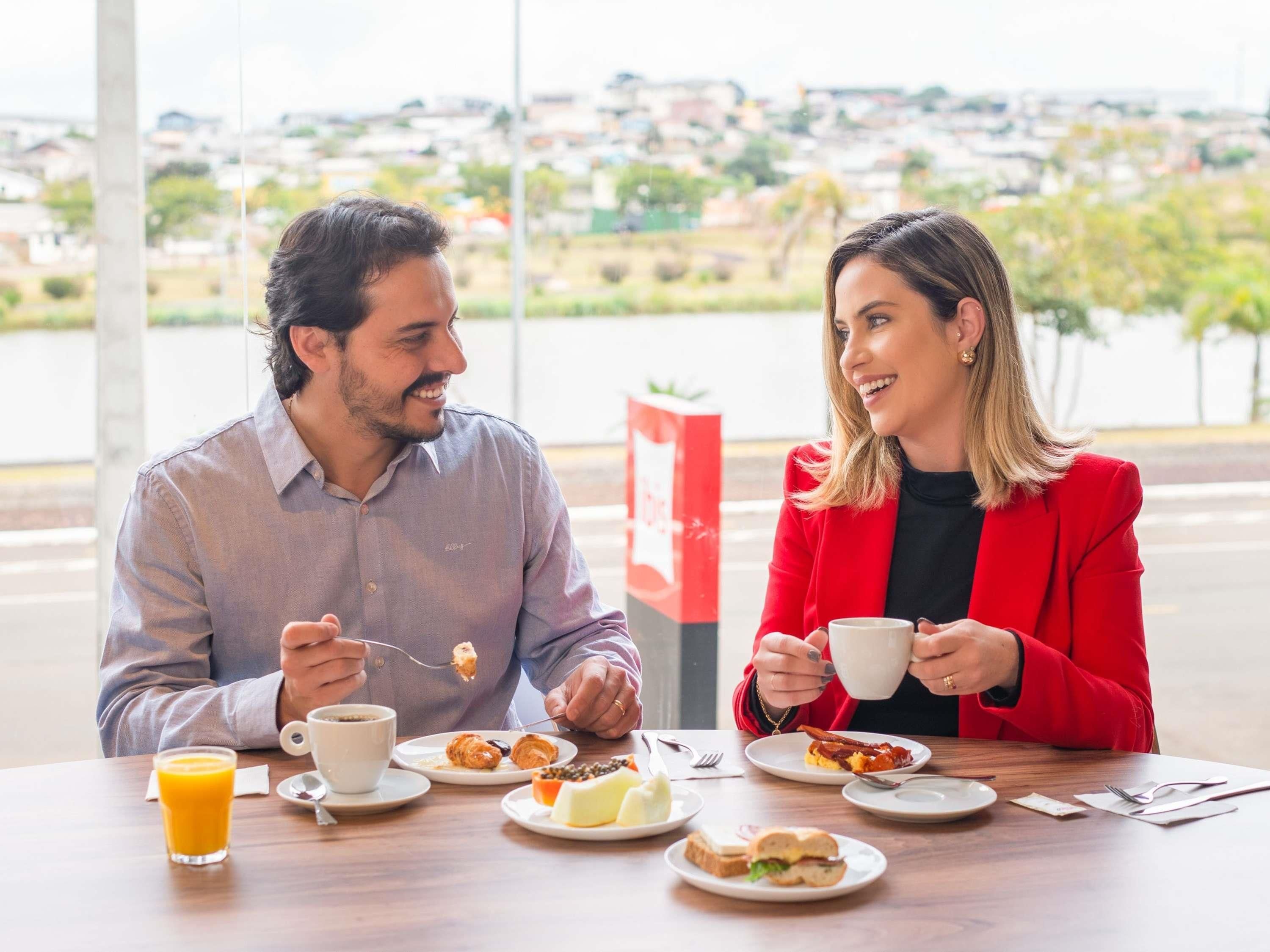 Dos personas cenando en una mesa con vista a un paisaje urbano.