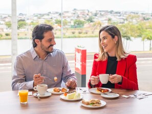 Two people dining at a table with a view of a cityscape. - Ibis Guarapuava (Guarapuava)