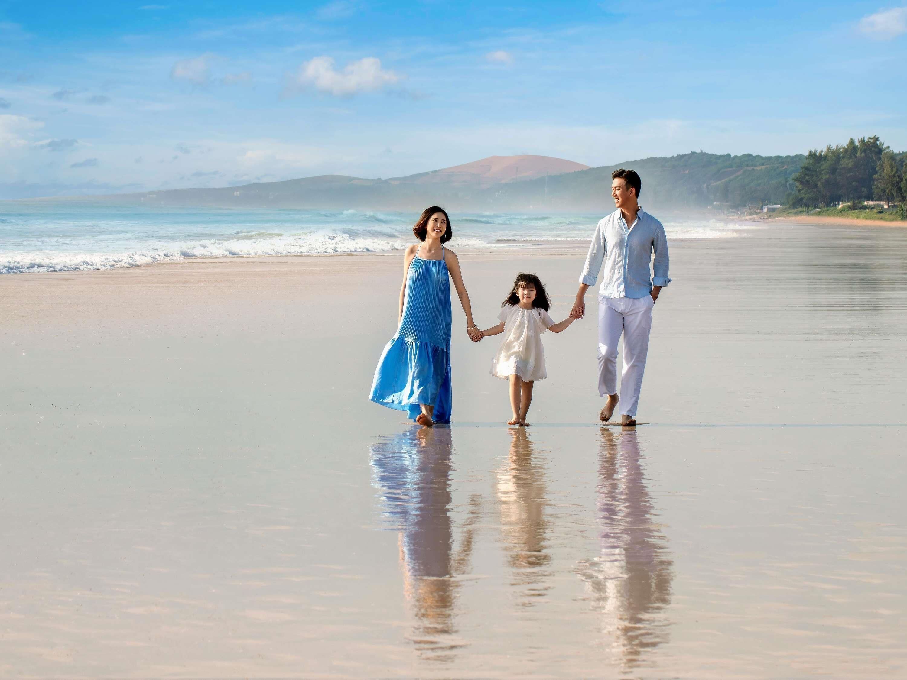 A beach with a family walking on the sand.