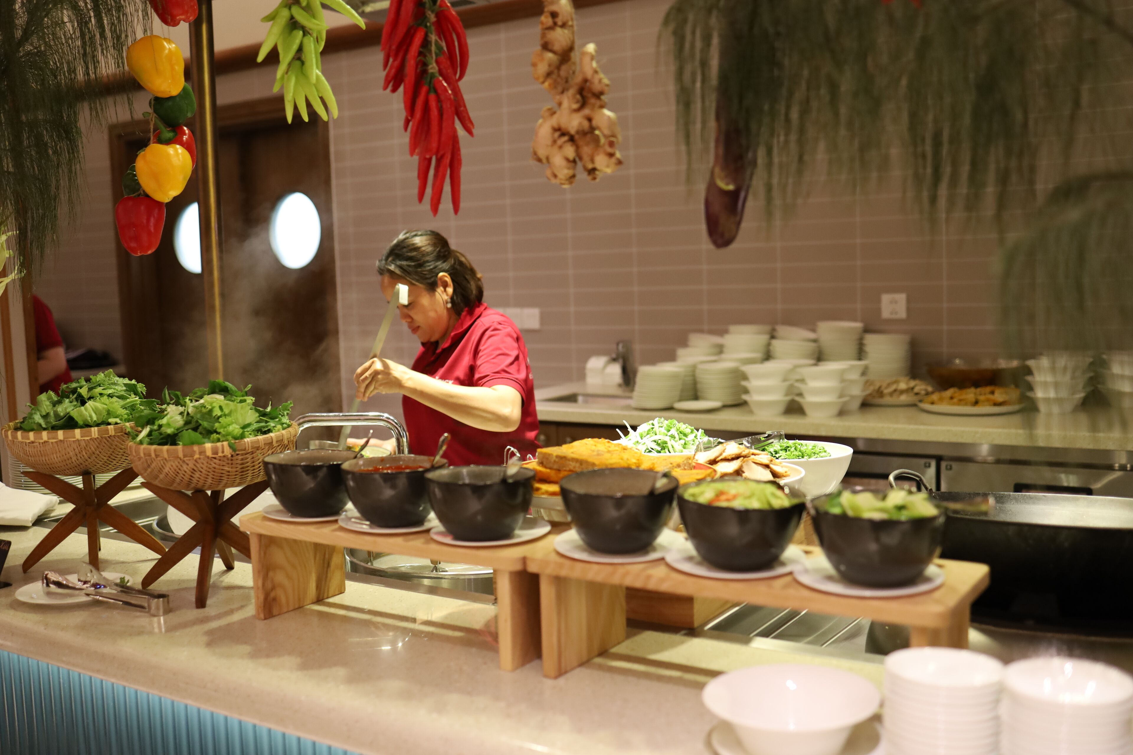 A buffet setup with various food items and a person serving.