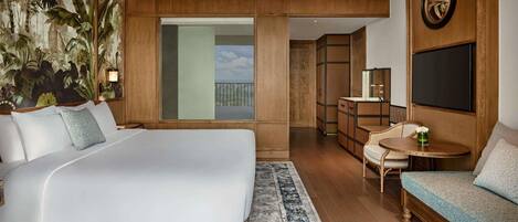 Un dormitorio amplio con una cama grande, ventilador de techo, vista al balcón y una zona de comedor con mesa y sillas.