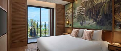 A spacious bedroom with a large bed, a ceiling fan, and a view of a tropical landscape through a sliding door.