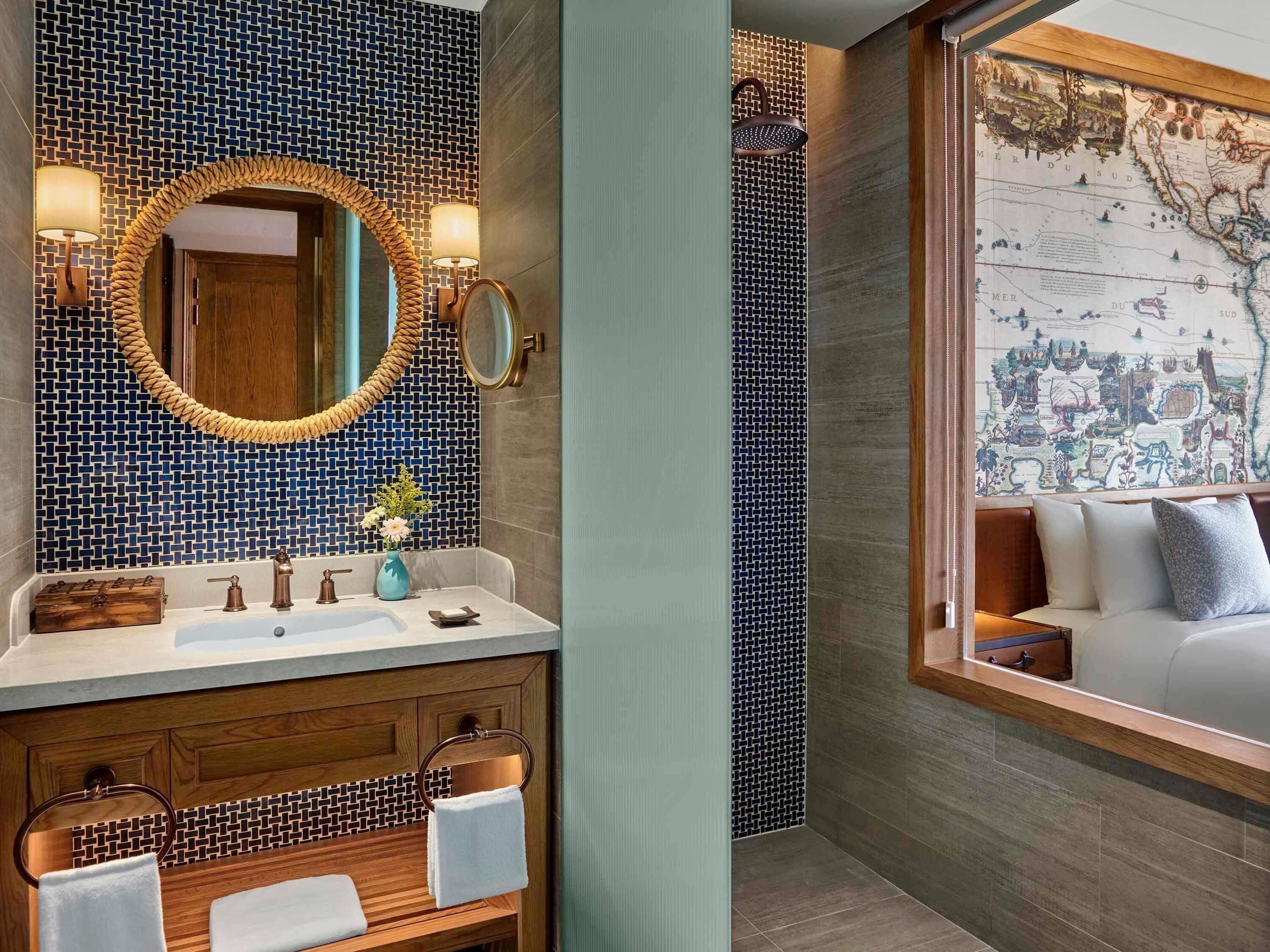 A bathroom with a large mirror, two wall-mounted lights, a wooden vanity, and a map on the wall.