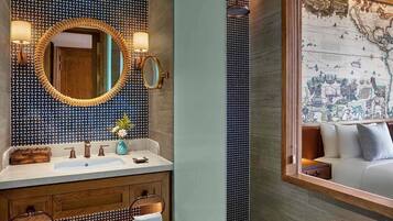 A bathroom with a large mirror, two wall-mounted lights, a wooden vanity, and a map on the wall.