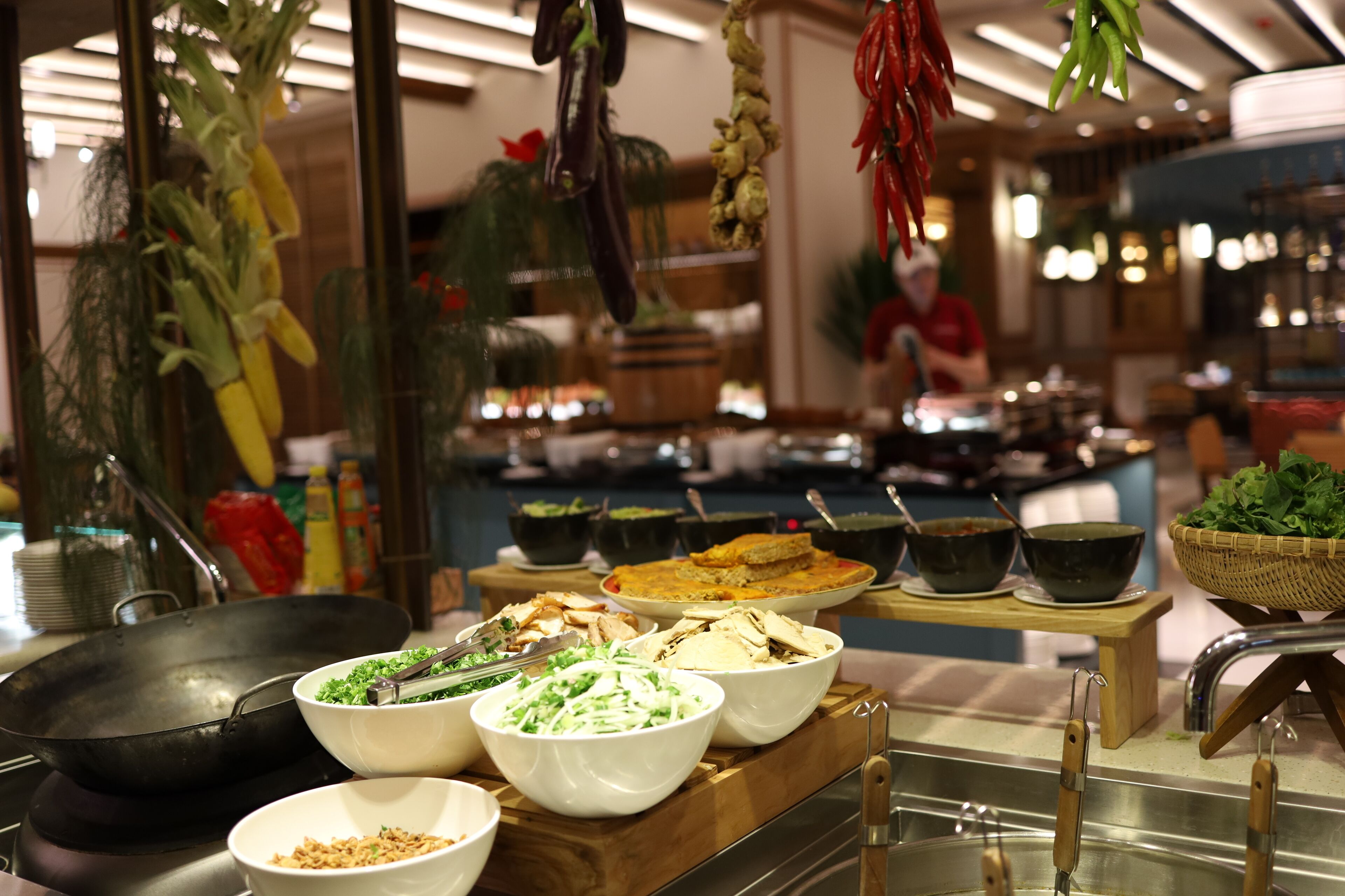 En buffet med forskellige retter og en wok på en kogeplade.