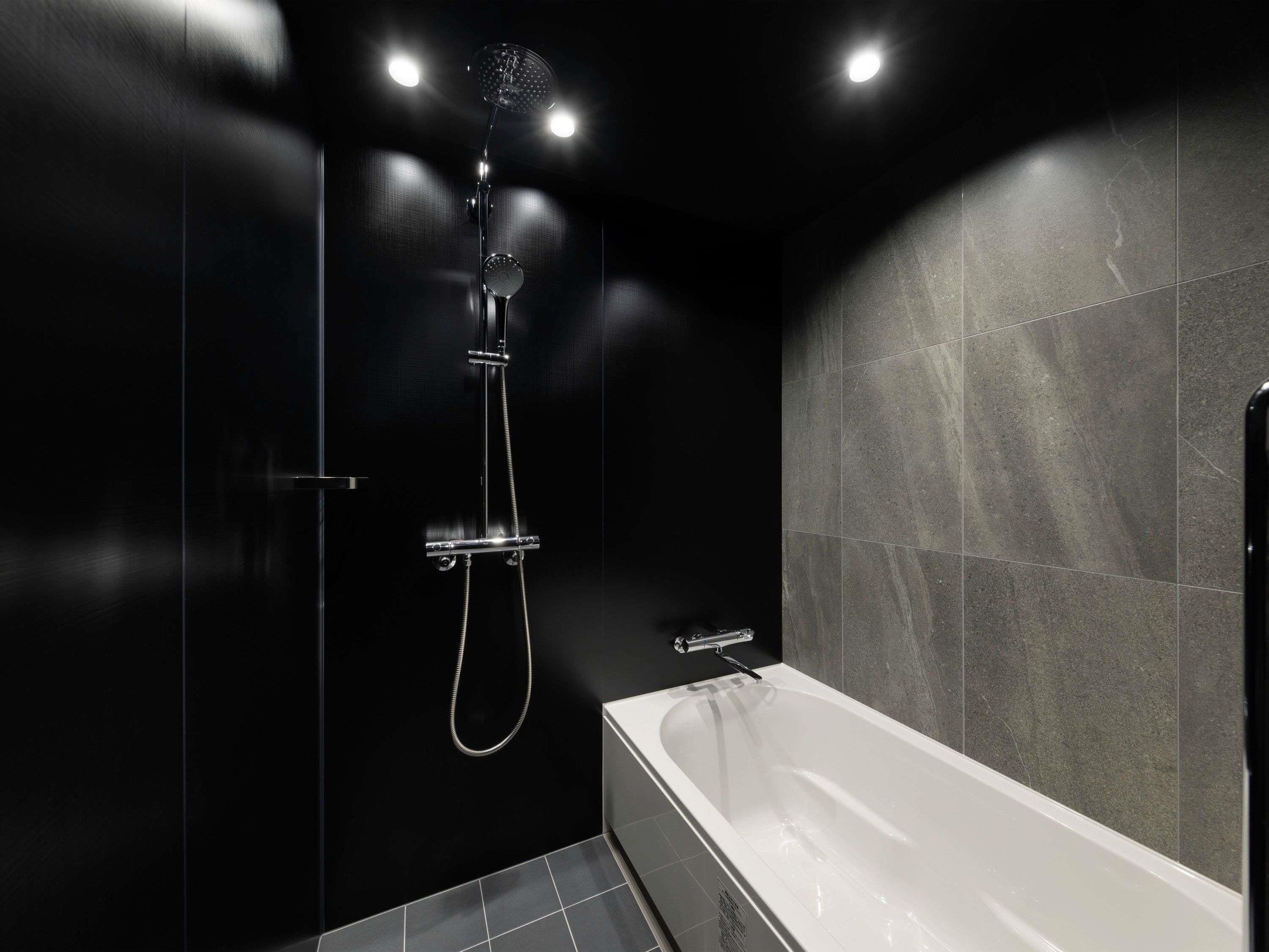 Un bagno moderno con una vasca, una doccia con soffione manuale e un rubinetto a parete.