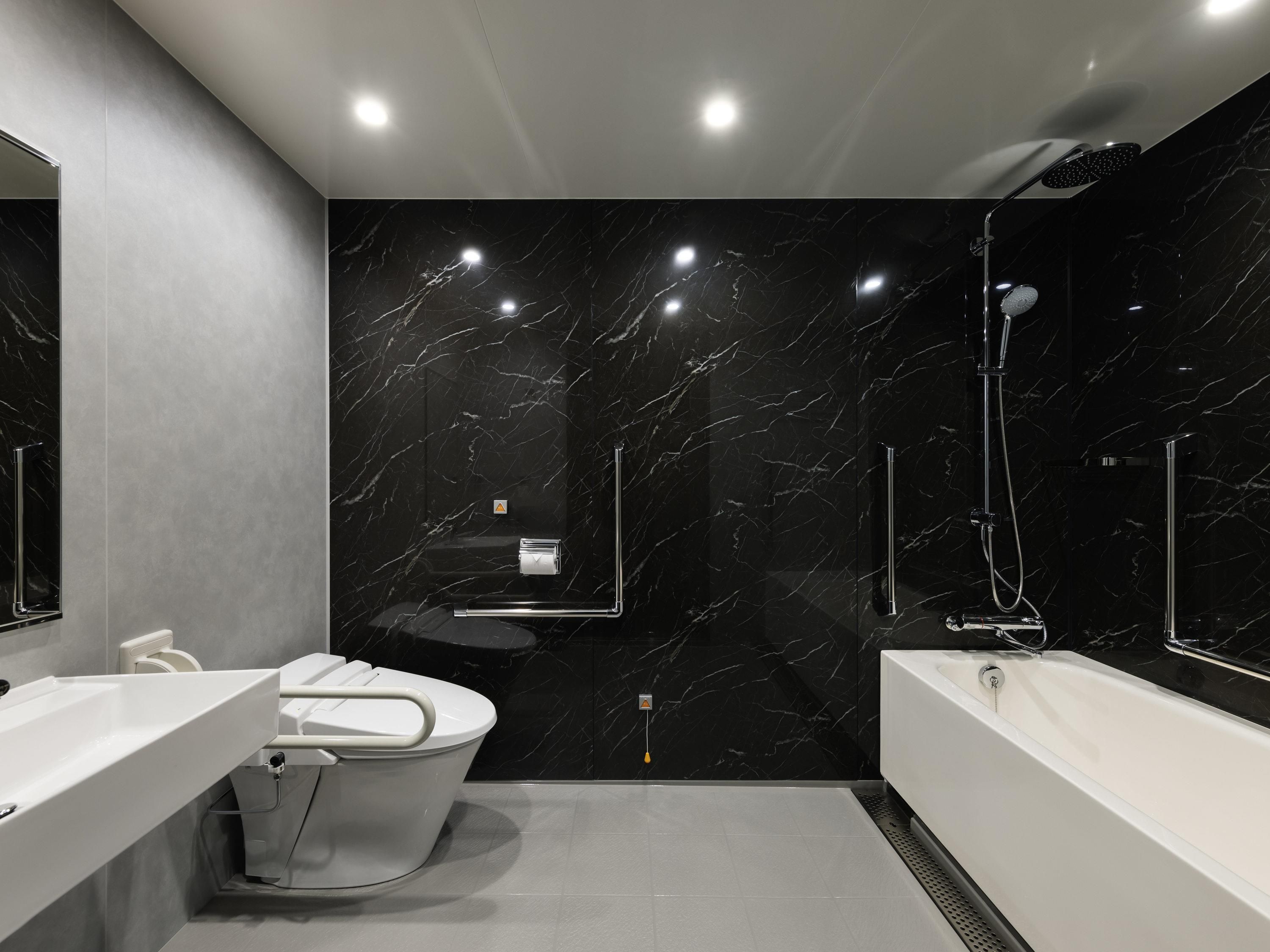 A modern bathroom with a black marble wall, a bathtub, a shower, and two sinks.