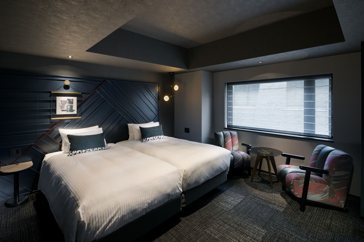 A modern hotel room with a large bed, a desk, and a chair.