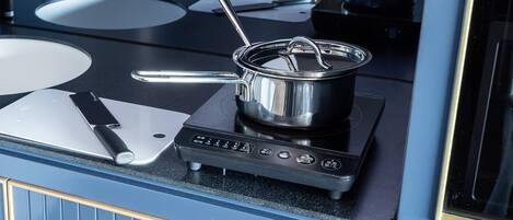 A modern kitchen with a black stovetop, a pot on the burner, and a cutting board with a knife.