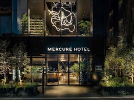 L’extérieur de l’hôtel Mercure présente un design moderne, avec une enseigne au néon et une façade en verre.