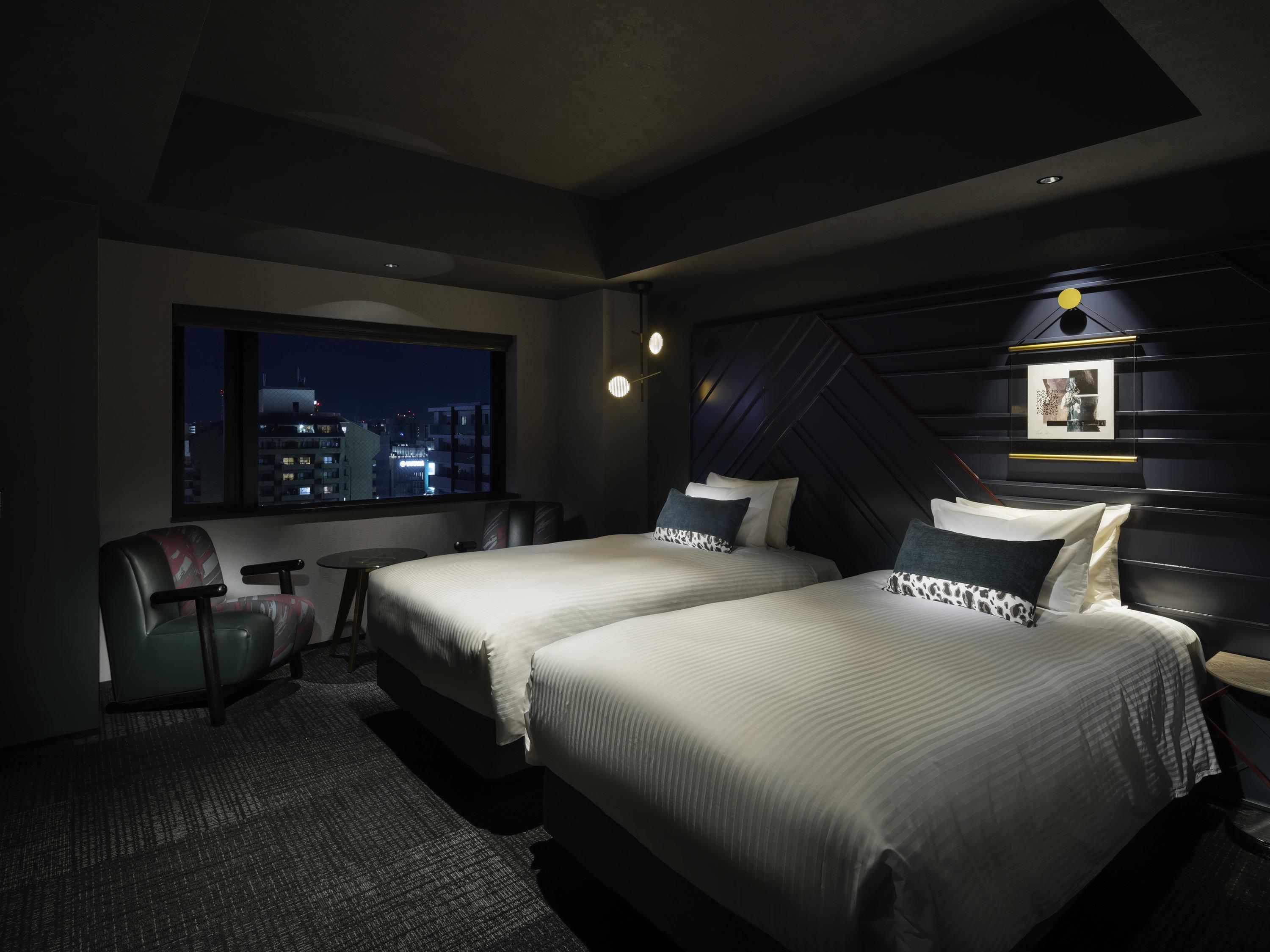 A hotel room with two beds, a desk, a chair, a city view, and a modern ceiling design.
