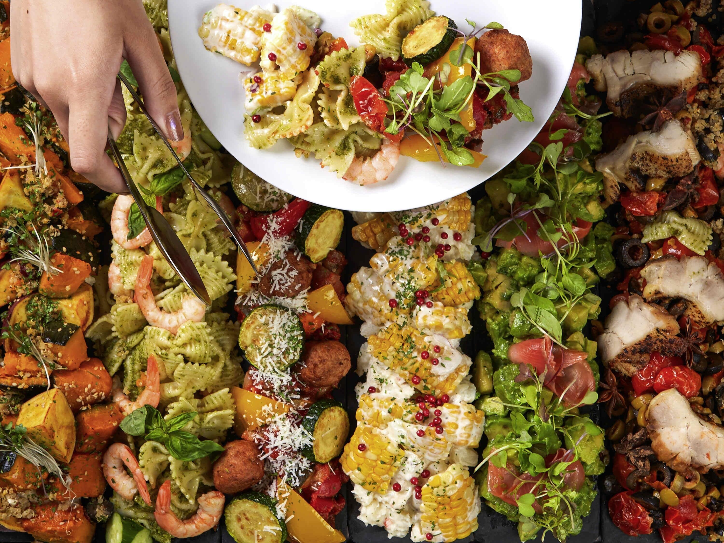 A variety of dishes including pasta, shrimp, and vegetables.