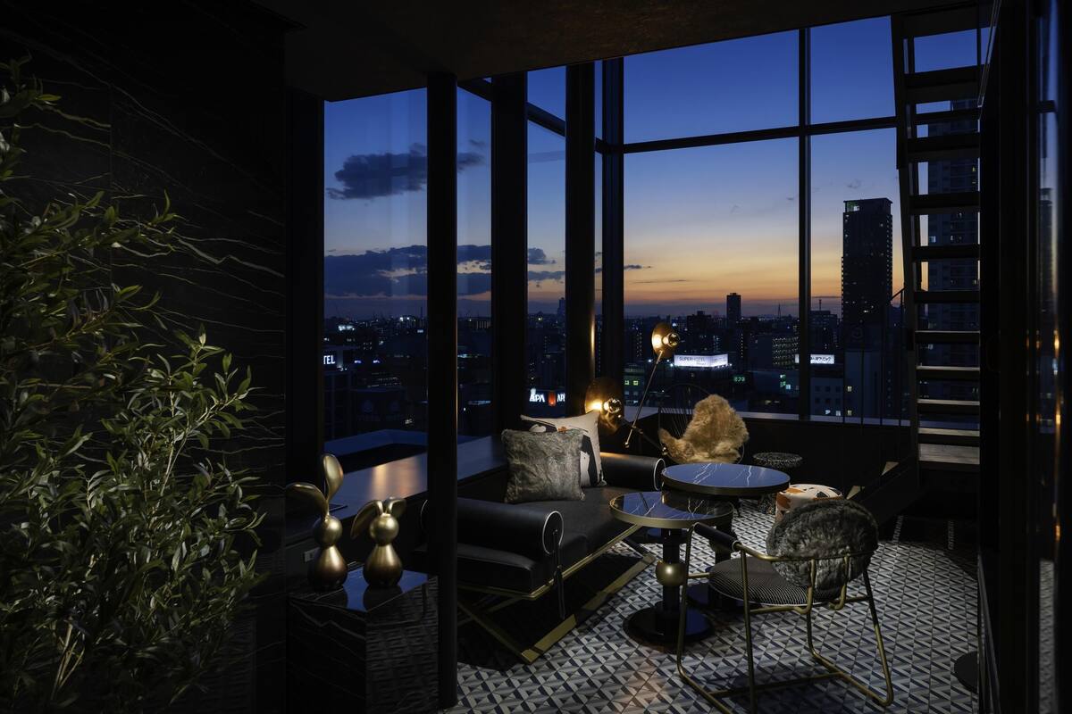 Un salón moderno con vistas a la ciudad, que incluye un sofá, sillas y una mesita.