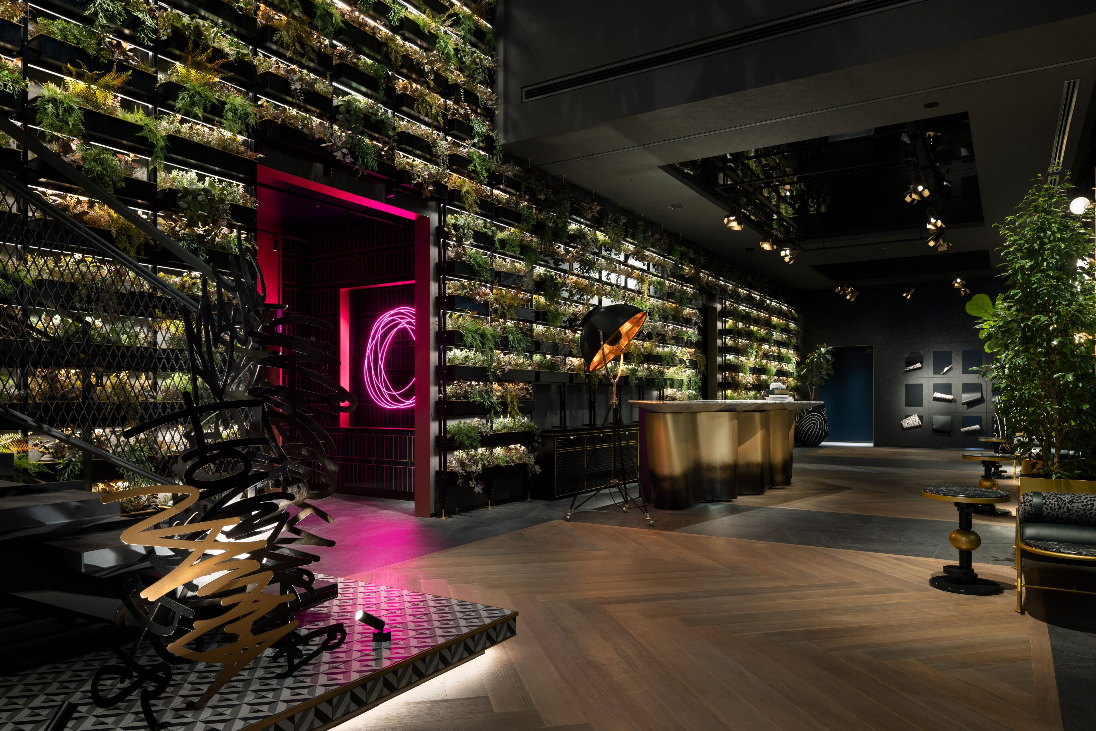 A modern interior with a vertical garden wall, a neon-lit entrance, and a bar area.